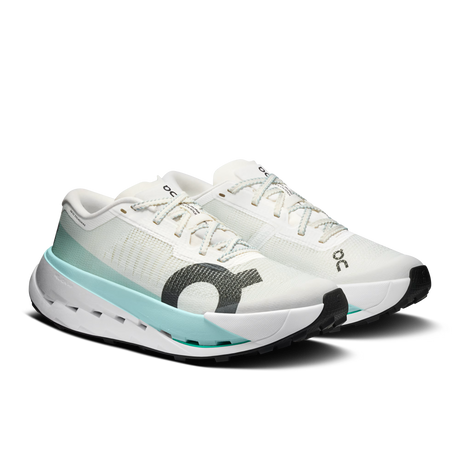A pair of white running shoes with a light blue and gray accent design, featuring the 'ooc' logo on the side and tongue, set against a plain white background. - On Cloudultra Pro Shoes (Women's) - Ivory/Celeste