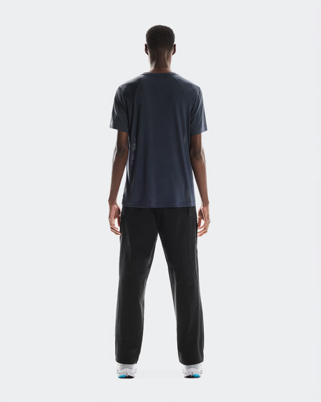 Person wearing a dark gray t-shirt and black pants on a white  - On Trail-T (Men's) - Navybackground