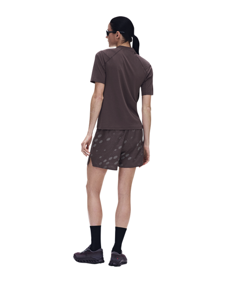 A woman shown from the back wearing a brown short-sleeve athletic shirt and matching brown shorts with a subtle tonal pattern, black socks, and running shoes against a plain white background. - On Trail-T Solar (Women's) - Mulberry