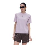 A woman modeling a light purple short-sleeve athletic t-shirt with a small black logo on the chest, paired with dark patterned shorts, against a solid white background. - On Trail-T Solar (Women's) - Foxglove
