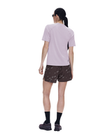 A model shown from the back wearing a light purple short-sleeve athletic shirt, brown patterned running shorts, black socks, and trail running shoes against a solid white background. - On Trail-T Solar (Women's) - Foxglove