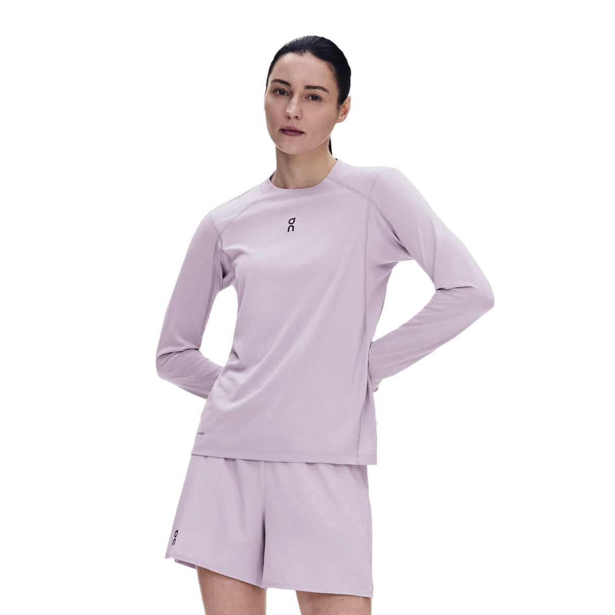 A woman modeling a light lavender athletic long-sleeve top and matching shorts against a plain white background. - On Trail Long-T Solar (Women's) - Foxglove