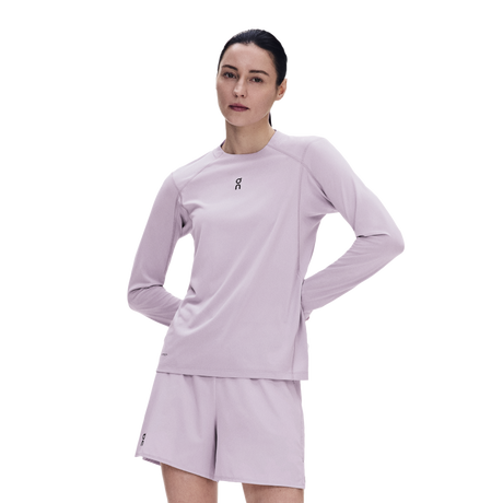 A woman modeling a light lavender athletic long-sleeve top and matching shorts against a plain white background. - On Trail Long-T Solar (Women's) - Foxglove