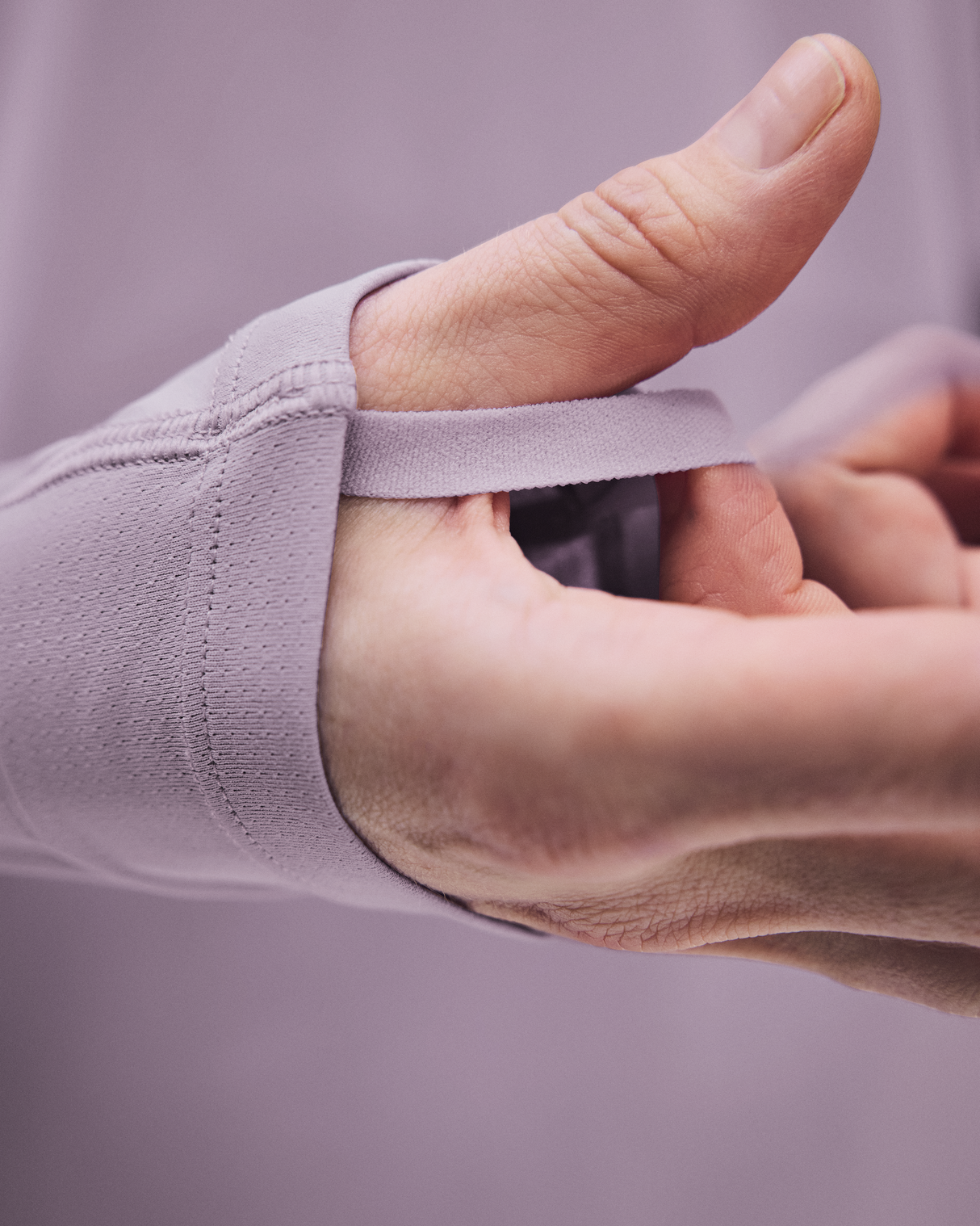 A close-up of a person's hand and wrist wearing a light lavender compression sleeve with an elastic wrap. - On Trail Long-T Solar (Women's) - Foxglove