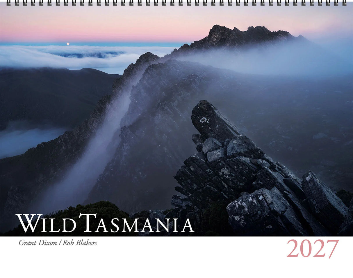 A 2027 wall calendar titled 'Wild Tasmania' featuring a dramatic mountain landscape with mist, rocky peaks, and a pink-and-blue dawn sky. The cover has a white band at the bottom with the title in large white letters and the year '2027' in red. - Rob Blakers Wild Tasmania 2027 Large Calendar
