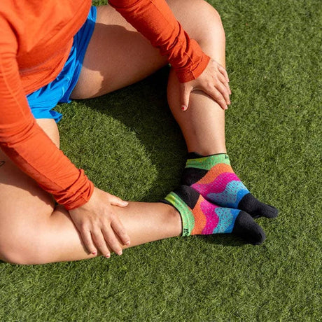 Person wearing colorful patterned socks on a grassy field - Injinji Spectrum Run Lightweight No-Show Toesocks (Women's) - Sprinkles