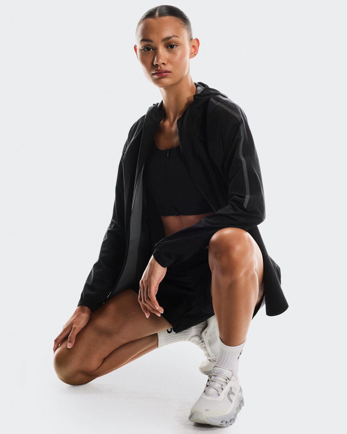 Person wearing a black outfit with white sneakers on a white  - On Performance Jacket (Women's) - Blackbackground