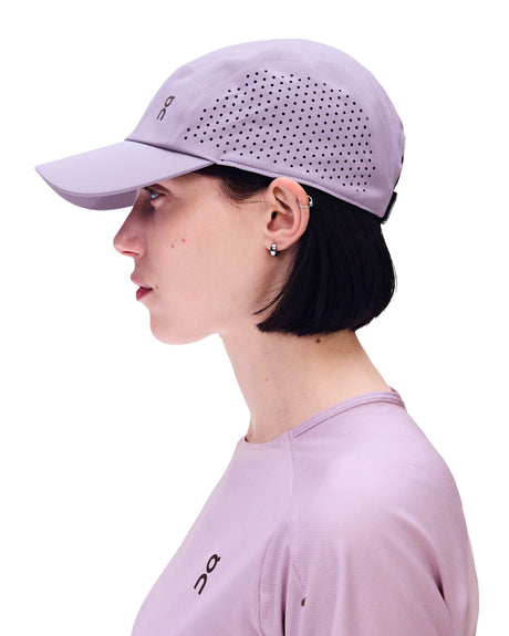 A woman in profile wearing a light purple athletic cap with perforated side panels and a matching light purple long-sleeve top, shown against a plain white background. - On Lightweight Cap - Mallow
