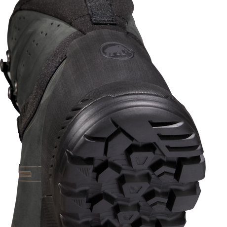 Close-up detail shot of the outsole and heel area of a black snowboard boot, showing the tread pattern and a circular logo embossed on the heel counter. - Mammut Mercury Tour II High GORE-TEX (Men's) - Black/Black