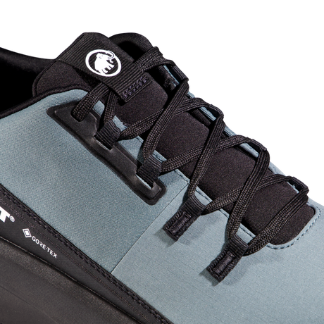 Close-up of a trail running shoe showing the side profile, featuring a slate blue-gray upper, black laces, black plastic lace guard, and a black heel section with a visible GORE-TEX logo. - Mammut Aenergy Hike Low GORE-TEX (Men's) - Strata/Black