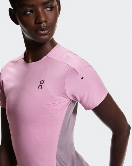 Person wearing a pink athletic shirt with a brand logo on a light gray  - On Performance-T (Women's) - Dewberry/Sakurabackground