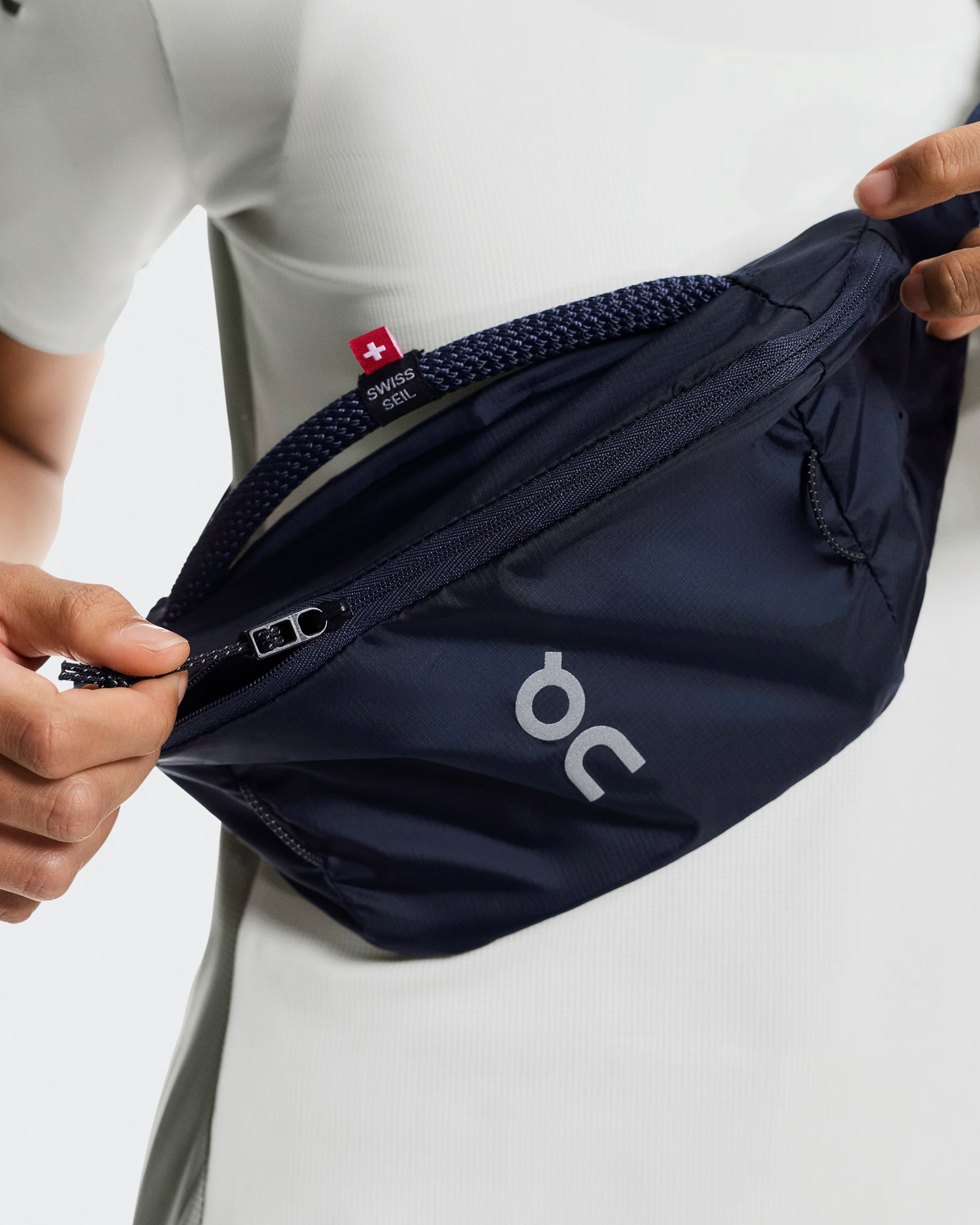 Navy waist bag with 'on' logo held by a person on a light gray background - On Waist Pack 2L Lite - Navy