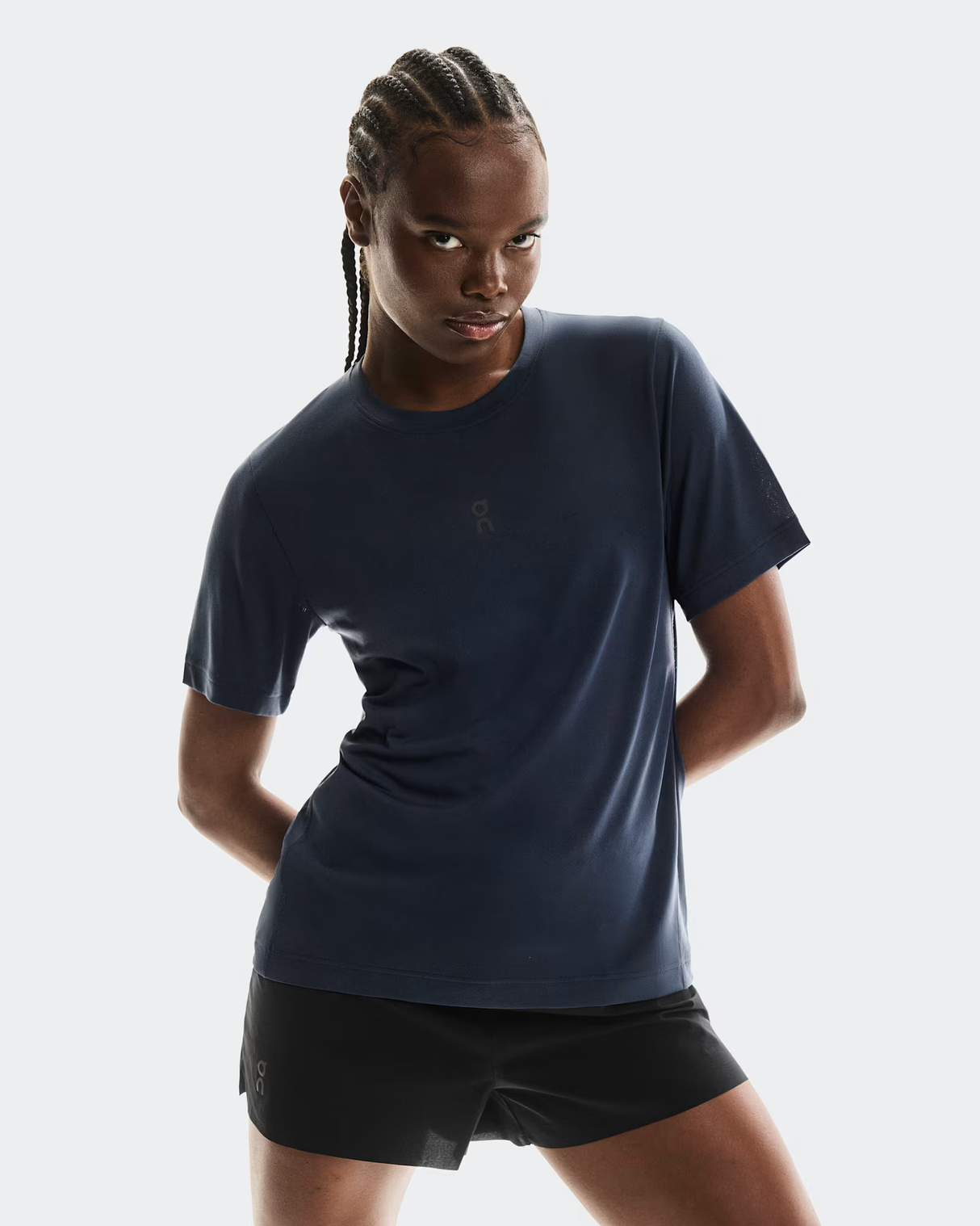 Person wearing a navy blue athletic shirt and black shorts on a light gray background - On Trail-T (Women's) - Navy