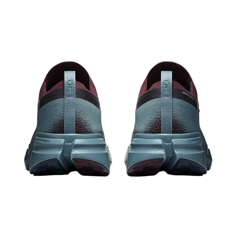 A pair of running shoes shown from the back, featuring a textured slate blue-green upper with dark burgundy accents and a thick matching midsole. - On Cloudsoma Shoes (Men's) - Urchin/Agave