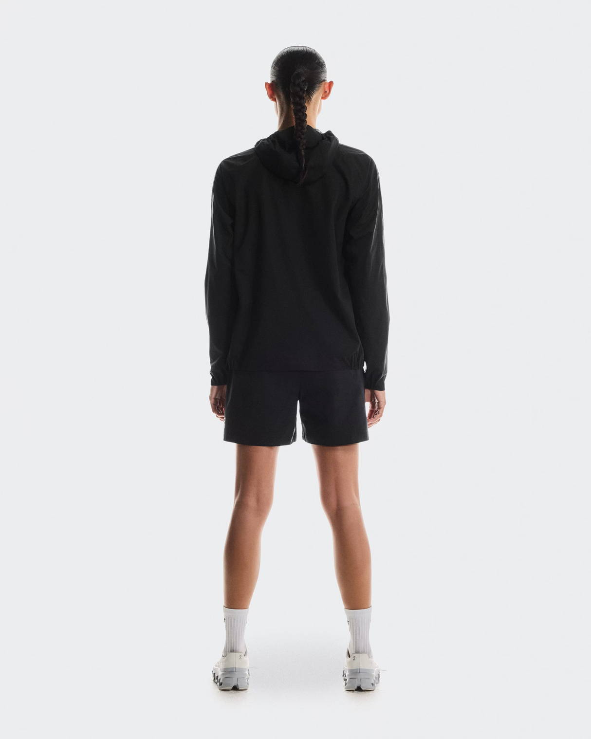 Person wearing a black hoodie and shorts on a white background - On Performance Jacket (Women's) - Black