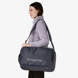 Woman carrying a Patagonia duffel bag on a white background - Patagonia Black Hole Mini MLC Pack 30L - Smolder Blue w/Forge Grey