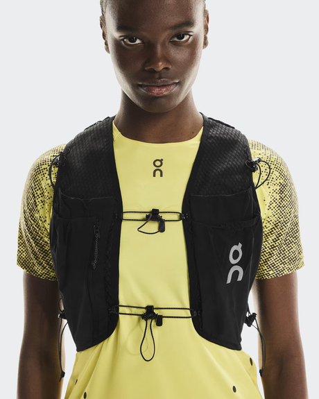 Person wearing a black running vest and yellow athletic shirt on a white background - On Ultra Vest Pro (Unisex) - Black