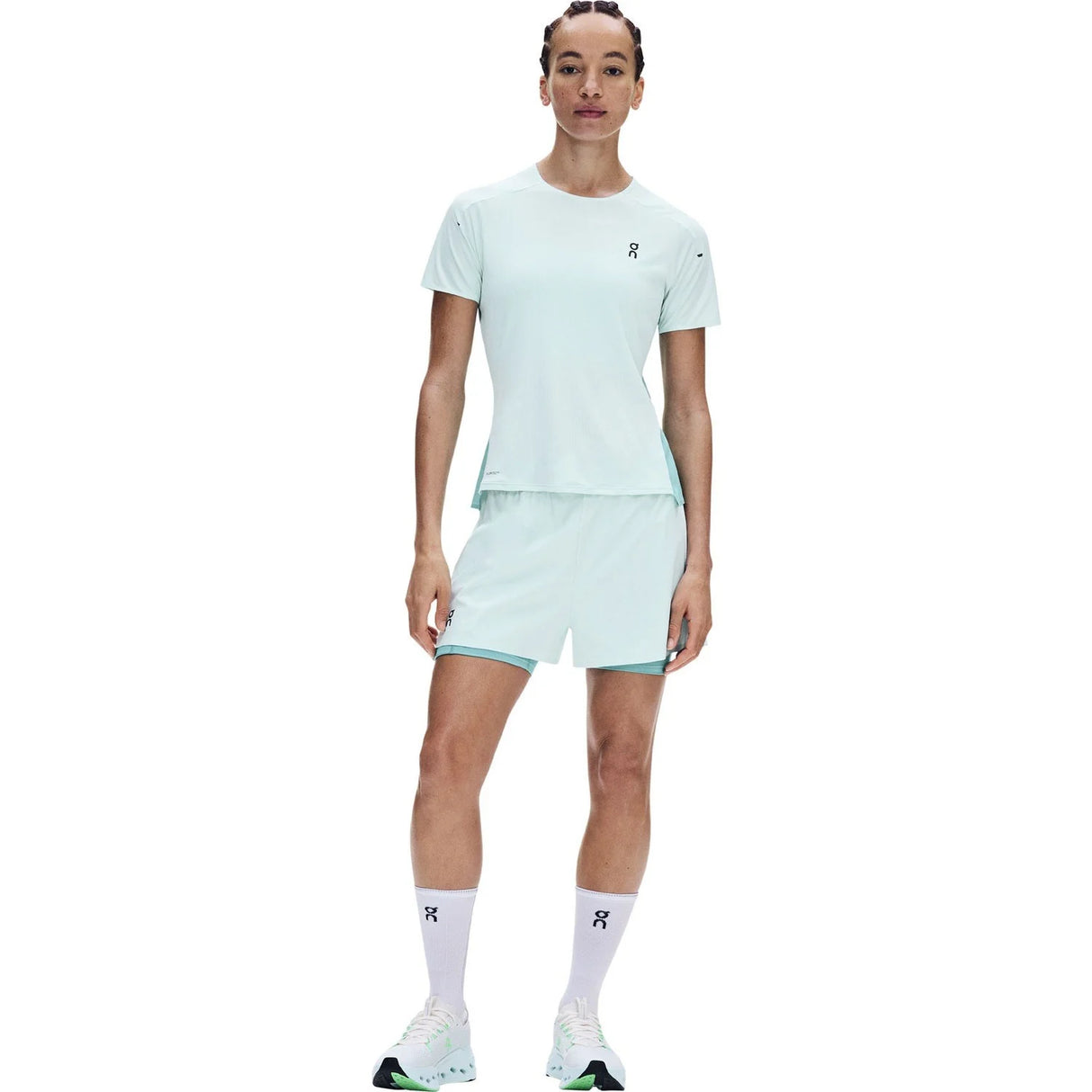 A model wearing a light mint green athletic set consisting of a short-sleeve t-shirt and matching shorts, paired with white socks and running shoes, against a plain white background. - On Performance-T (Women's) - Flurry/Aquamarine