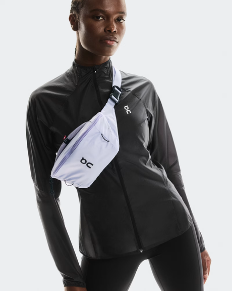 Person wearing a black jacket with a white fanny pack on a light gray background - On Waist Pack 2L Lite - Thistle