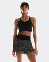Woman wearing a black sports bra and patterned shorts on a white background - On Ultra Shorts (Women's) - Iron/Lime