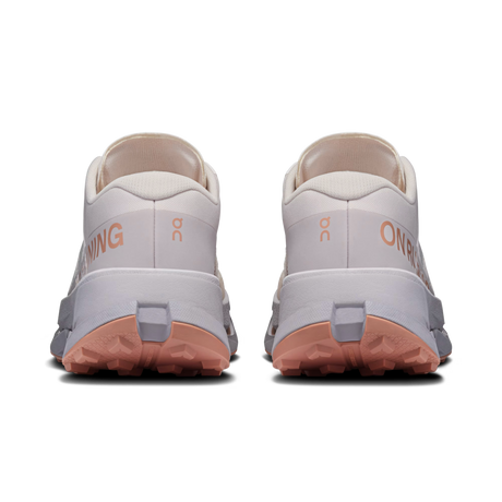 A pair of On Running trail shoes shown from the back, featuring a light gray and off-white upper, peach-pink midsoles, and a coral-pink outsole. - On Cloudultra 3 Shoes (Women's) - Oyster/Ether