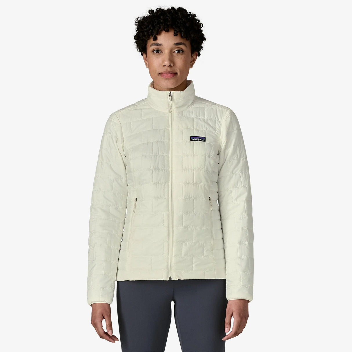 Person wearing a light-colored jacket with a visible brand logo on a white background - Patagonia Nano Puff Jacket (Women's) - Birch White