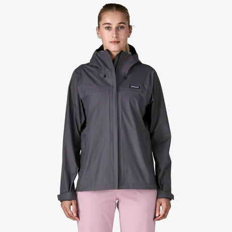 Person wearing a gray rain jacket with a visible brand logo on a white background - Patagonia Torrentshell 3L Rain Jacket (Women's) - Smolder Blue