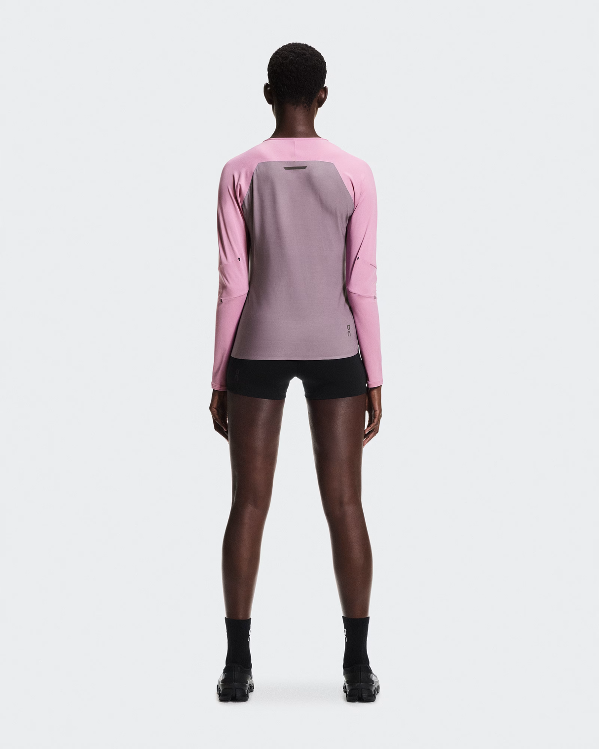 Person wearing a pink and gray athletic outfit on a white background - On Performance Long-T (Women's) - Dewberry/Sakura