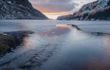 A scenic winter landscape with a frozen or partially frozen lake between snow-dusted mountains, under a sunset sky reflected in the water. - Rob Blakers Tasmanian Landscapes Calendar