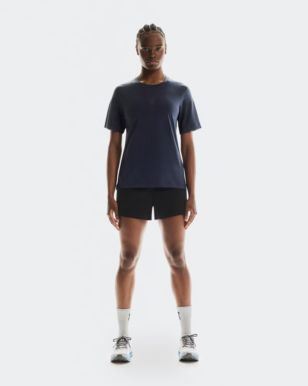 Person wearing a dark blue t-shirt, black shorts, and white socks on a white background - On Trail-T (Women's) - Navy