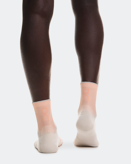 Person wearing dark tights and light-colored socks on a white background - On Performance Run Sock Mid (Unisex) - Pearl/Sunstone