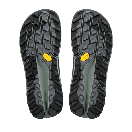 A pair of hiking shoe soles shown from the bottom, featuring a rugged black and dark gray tread pattern with a small yellow Vibram logo on each side, set against a plain white background. - Altra Olympus 7 Hike Mid GORE-TEX Boots (Women's) - Castlerock