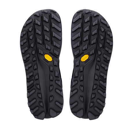 A pair of black Vibram outdoor sandals shown from the sole view, featuring deep lugs and a small yellow Vibram logo on each side, set against a plain white background. - Altra Olympus 7 Shoes (Men's) - Black/Dark Shadow/Black