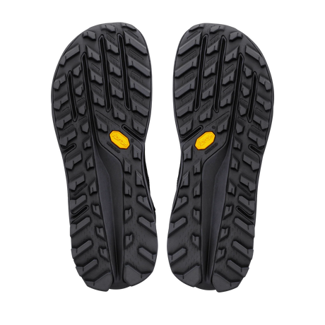 A pair of black rugged outdoor shoe soles shown from the bottom, featuring deep lugs and small yellow Vibram logos near the rear. - Altra Olympus 7 Hike Mid GORE-TEX Boots (Men's) - Black/Shadow