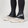 Black ankle covers worn over white running shoes on a light gray background - Altra Trail Gaiters - Black/Silver/Grey