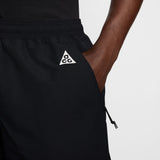 Close-up of a person wearing black athletic shorts with a white triangular ACG logo on the left hip, shown against a light gray studio background. - Nike ACG Reservoir Goat Shorts (Men's) - Black/Anthracite/Summit White