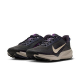 A pair of Nike running shoes in dark gray and black with purple accents and a beige Swoosh and midsole, shown on a clean white background. - Nike ACG Pegasus Trail Shoes (Men's) - Gridiron/Cream II-Racer Blue