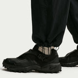 Black Nike shoes worn with black pants on a white background - Nike ACG Dolomiti Pants (Women's) - Black/Summit White