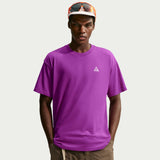 A man wearing a bright purple short-sleeve crewneck t-shirt with a small white geometric logo on the left chest, paired with brown pants and an orange and white cap with sunglasses. - Nike ACG Dri-FIT T-Shirt (Men's) - Bold Berry/Summit White
