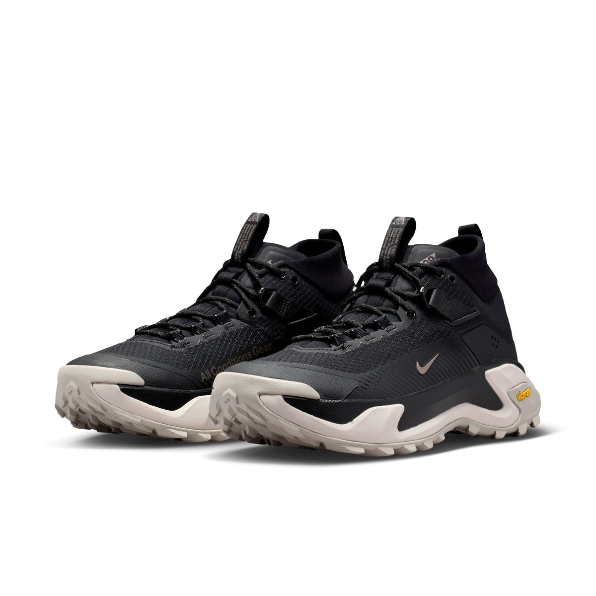 A pair of Nike high-top athletic sneakers in black with off-white midsoles and a small yellow Vibram badge, shown on a clean white background. - Nike ACG Zegama Hike Shoes (Men's) - Black/Ironstone-Cream II