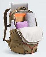 A tan BOREA backpack shown open, filled with travel items including a silver laptop, orange notebook, gray rolled blanket, purple pouch, and white bottle, on a light gray studio background. - The North Face Borealis Backpack - Cedar/Lava Red