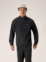 A man wearing a black Arc'teryx zip-up jacket and matching black pants, paired with a light beige baseball cap, standing against a plain light beige studio background. - Arc'teryx Gamma Jacket (Men's) - Black