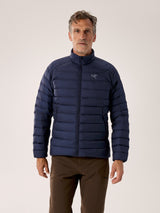 Man wearing a blue puffer jacket with a brand logo on a light gray background - Arc'teryx Cerium Jacket (Men's) - Black Sapphire