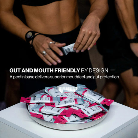 A plate of ALJAB branded pectin packets sits on a white table, with a cropped view of two people in black athletic wear reaching toward the packets. White text reads 'GUT AND MOUTH FRIENDLY BY DESIGN' and 'A pectin base delivers superior mouthfeel and gut protection. - Pillar Performance Energy Gel 30