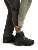 A close-up of a person's lower legs wearing black hiking boots, dark gray pants, and an olive green crew sock with the brand name 'Trek' partially visible. - Icebreaker Merino Hike+ Light Crew Socks (Women's) - Lichen/Dark Loden