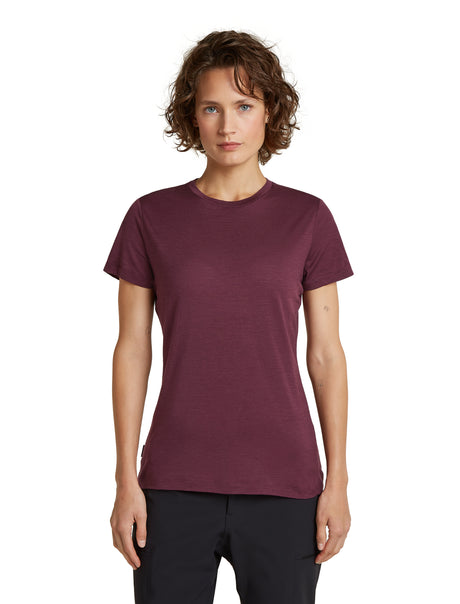 A woman with short brown curly hair wearing a short-sleeve crewneck t-shirt in heathered burgundy, paired with black pants, standing against a solid white background. - Icebreaker Merino 150 Tech Lite Short Sleeve T-Shirt (Women's) - Dark Berry
