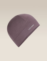 A single knit beanie hat in a muted dusty purple color, featuring the white 'icebreaker' logo on the side, set against a solid light beige background. - Icebreaker Merino 200 Oasis Beanie (Unisex) - Grey Plum