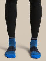 A close-up of a person's legs wearing black leggings and bright blue athletic socks with dark navy heel and toe sections, set against a solid beige background. - Icebreaker Merino Run+ Ultralight Mini Socks (Men's) - Lazurite/Midnight Navy