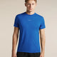 A man wearing a bright blue short-sleeve athletic t-shirt with a small white logo on the chest, paired with black shorts, against a solid beige background. - Icebreaker Merino Blend 125 Cool-Lite Speed Short Sleeve T-Shirt (Men's) - Lazurite
