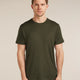 Man wearing a green t-shirt against a beige background - Icebreaker Merino 150 Tech Lite Short Sleeve T-Shirt (Men's) - Dark Loden